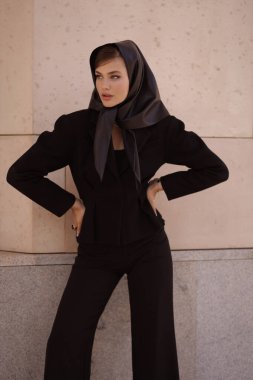 Uzun siyah saçlı, şık siyah takım elbiseli, şık, antika bir villada poz veren güzel bir kadının moda fotoğrafı.