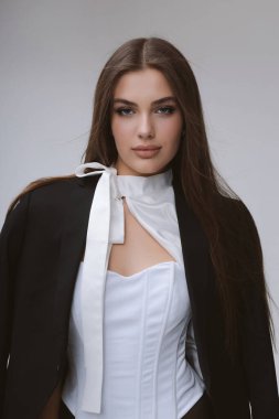 Güzel, uzun siyah saçlı, şık elbiseli, beyaz moda bluzu ve siyah etekli bir kadının moda fotoğrafı stüdyo da poz veriyor.