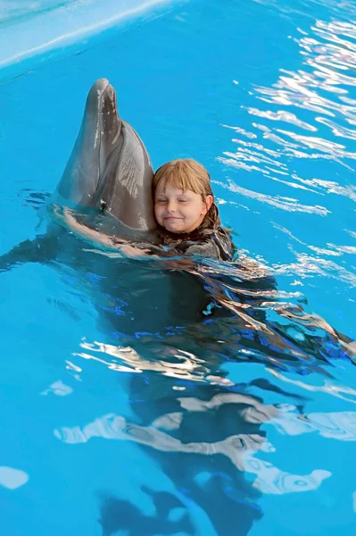 The small girl hugs a dolphin at the dolphin therapy session