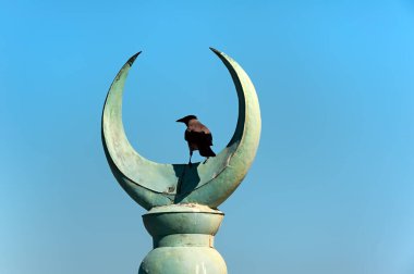 Üzerinde karga olan hilal şeklinde bir minare.