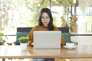 Kafede bilgisayar kullanan genç bir kadın.