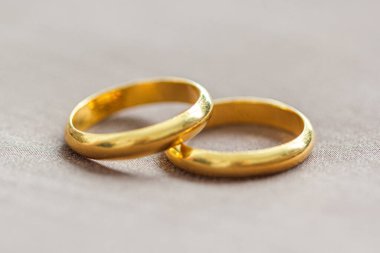 Kahverengi arka planda iki altın yüzük.