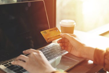 Kredi kartı tutan ve bilgisayarla çalışan bir kadın. Mobil Alışveriş. Mutlu kadın evde online alışveriş yapıyor.