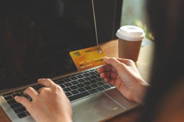 Kredi kartı tutan ve bilgisayarla çalışan bir kadın. Mobil Alışveriş. Mutlu kadın evde online alışveriş yapıyor.