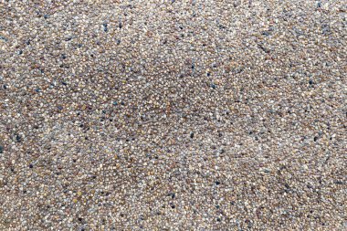 Döşemede ya da duvar yapımında kullanılan küçük çakıl taşı beton dokusuna yakın plan. Kaba, doğal yüzey çeşitli renkli taşlardan oluşur ve genellikle açık hava geçitlerinde, avlularda ya da mimari tasarımlarda bulunur..