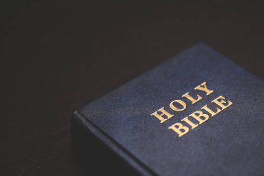 Close-up of a Holy Bible with gold lettering on a dark wooden table, symbolizing Christian faith, scripture, devotion, and spiritual reflection.
