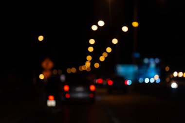 Parlayan araba ışıkları ve Bokeh sokak lambalarıyla bulanık gece trafik sahnesi rüya gibi bir şehir atmosferi yaratıyor..