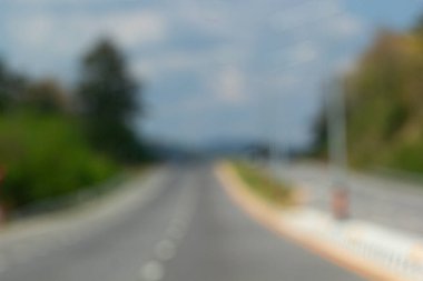 Otoyol manzarası bulanık, doğal çevre, yeşil ağaçlar ve mavi gökyüzü rüya gibi bir yolculuk ve yolculuk havası yaratıyor..