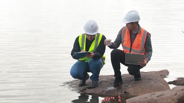 環境2人のエンジニアが水源で働き 水源内の汚染物質をチェックし 再利用のための水試験結果を分析します — ストック動画