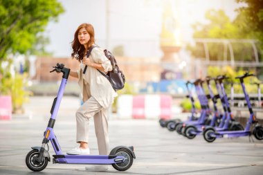 Takım elbiseli şık bir bayan ofis binalarında çalışmak için elektrikli scooter kullanıyor..