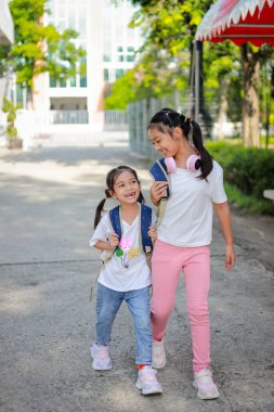 Sırt çantalı küçük Asyalı kız okula eğlenerek gidiyor. Bu da gelişimini arttırır ve öğrenme becerilerini geliştirir. Okula Dönüş Konsepti. 