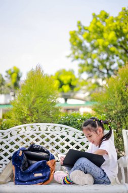 Küçük Asyalı kız, dersten sonra kitap okuyor. Ödev yapmayı öğreniyor. Bu da sınıfın gelişimini arttırıyor ve öğrenme becerilerini geliştiriyor. Okula Dönüş Konsepti.