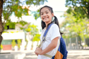 Sırt çantalı küçük Asyalı kız okula eğlenerek gidiyor. Bu da gelişimini arttırır ve öğrenme becerilerini geliştirir. Okula Dönüş Konsepti.