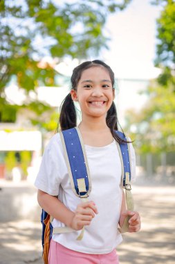 Sırt çantalı küçük Asyalı kız okula eğlenerek gidiyor. Bu da gelişimini arttırır ve öğrenme becerilerini geliştirir. Okula Dönüş Konsepti.