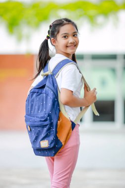 Sırt çantalı küçük Asyalı kız okula eğlenerek gidiyor. Bu da gelişimini arttırır ve öğrenme becerilerini geliştirir. Okula Dönüş Konsepti.