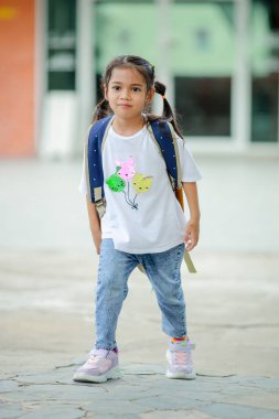 Sırt çantalı küçük Asyalı kız okula eğlenerek gidiyor. Bu da gelişimini arttırır ve öğrenme becerilerini geliştirir. Okula Dönüş Konsepti. 