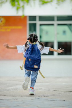 Sırt çantalı küçük Asyalı kız okula eğlenerek gidiyor. Bu da gelişimini arttırır ve öğrenme becerilerini geliştirir. Okula Dönüş Konsepti.