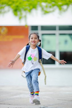 Sırt çantalı küçük Asyalı kız okula eğlenerek gidiyor. Bu da gelişimini arttırır ve öğrenme becerilerini geliştirir. Okula Dönüş Konsepti.