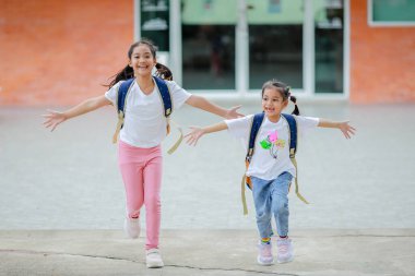 Sırt çantalı küçük Asyalı kız okula eğlenerek gidiyor. Bu da gelişimini arttırır ve öğrenme becerilerini geliştirir. Okula Dönüş Konsepti.