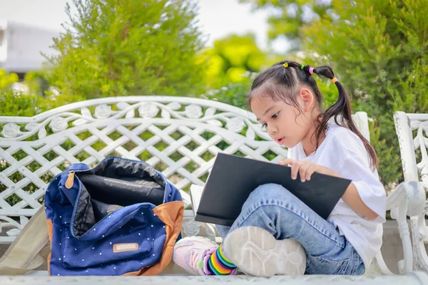 Küçük Asyalı kız, dersten sonra kitap okuyor. Ödev yapmayı öğreniyor. Bu da sınıfın gelişimini arttırıyor ve öğrenme becerilerini geliştiriyor. Okula Dönüş Konsepti.