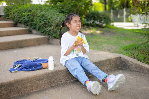 Κοριτσάκι Ασιάτισσα Που Κρατάει Και Τρώει Μπανάνα Στο Σχολείο Νιώστε — Φωτογραφία Αρχείου