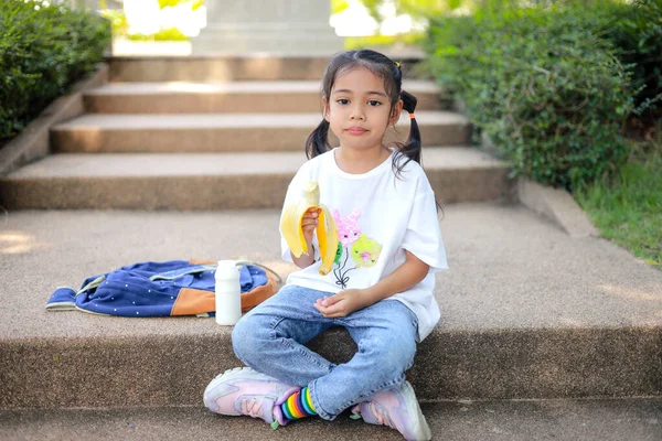Κοριτσάκι Ασιάτισσα Που Κρατάει Και Τρώει Μπανάνα Στο Σχολείο Νιώστε — Φωτογραφία Αρχείου