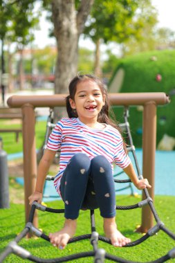 Küçük Asyalı kız, oyun parkında eğlenirken. Bu da sınıfın öğrenme becerilerinin dışında gelişimi ve gelişimi arttırır..