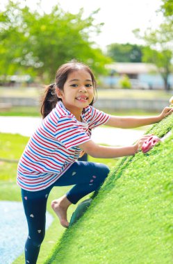 Küçük Asyalı kız, oyun parkında eğlenirken. Bu da sınıfın öğrenme becerilerinin dışında gelişimi ve gelişimi arttırır..
