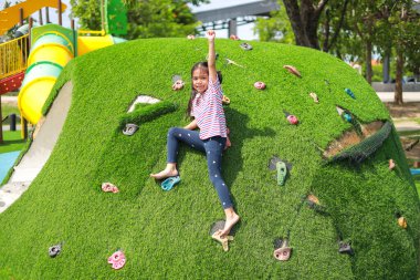 Küçük Asyalı kız, oyun parkında eğlenirken. Bu da sınıfın öğrenme becerilerinin dışında gelişimi ve gelişimi arttırır..