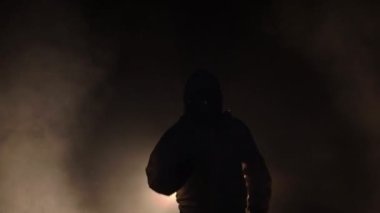 Koşan adam biyolojik tehlike kimyasalı giyip karanlık arka planda maske takıyor.
