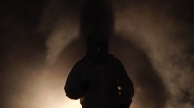 Koşan adam biyolojik tehlike kimyasalı giyip karanlık arka planda maske takıyor.