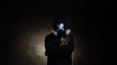 Biyolojik tehlike taşıyan kimyasal koruyucu kıyafet giyen ve karanlık arka planda maske takan bir adam.