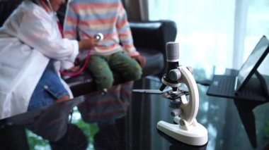 İki Asyalı çocuk evde doktorculuk oynuyor. 