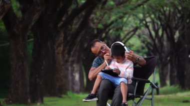 Asyalı baba ve oğul parkta oturup ders çalışıyorlar.