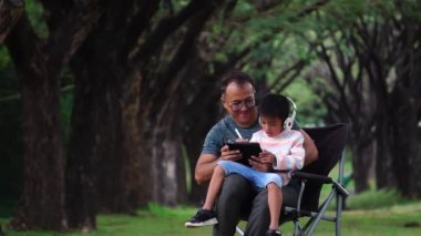 Asyalı baba ve oğul parkta oturup ders çalışıyorlar.