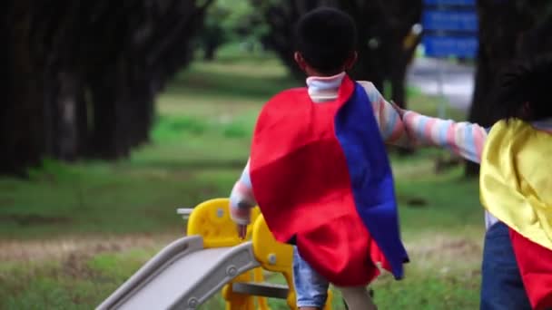 Två Små Asiatiska Barn Leker Lekplatsen Superhjältedräkter — Stockvideo