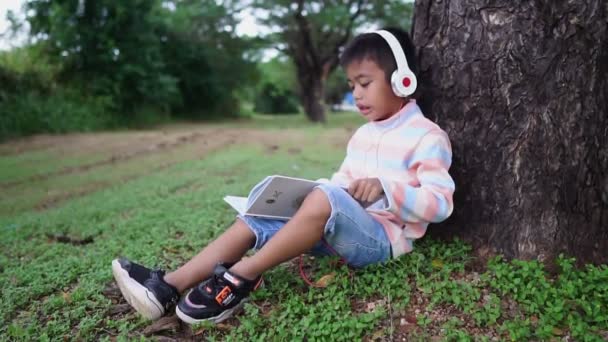 公園で勉強しているアジア系の少年 — ストック動画