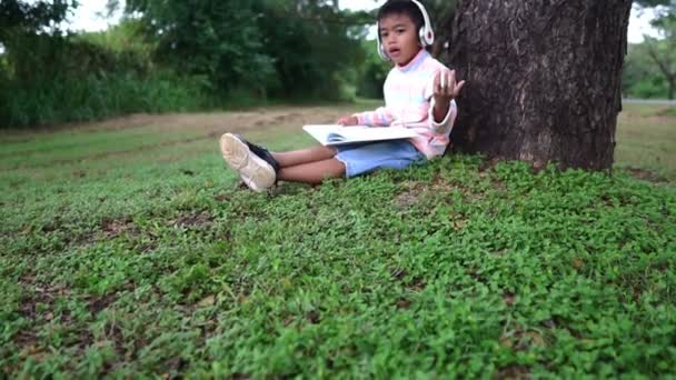 Asiatischer Junge Sitzt Park Und Studiert — Stockvideo