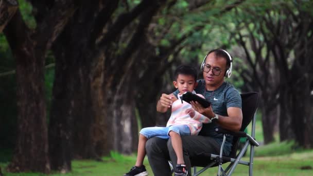 亚洲父亲和儿子坐在公园学习 — 图库视频影像