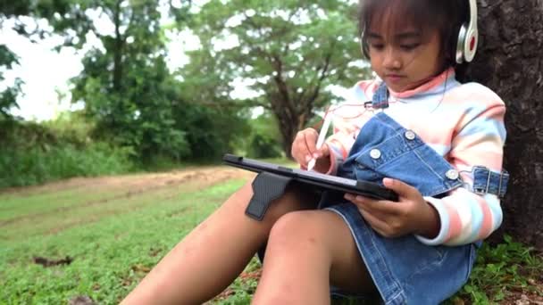 Asijské Holčička Sedí Parku Studuje Pomocí Tabletu — Stock video