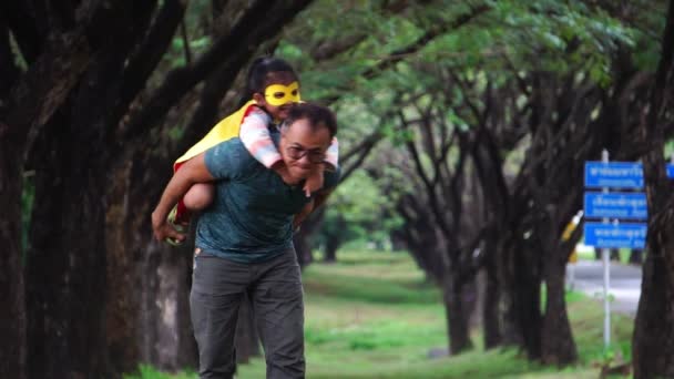 Asiatisk Far Leker Med Sin Lilla Dotter Superhjältedräkter Parken — Stockvideo