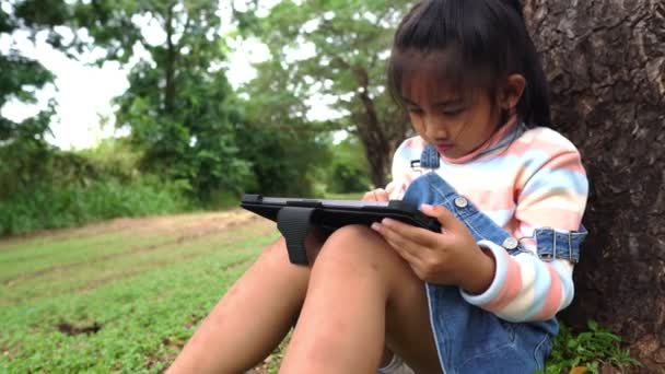 Azji Dziewczynka Siedzi Parku Studiuje Pomocą Tabletu — Wideo stockowe