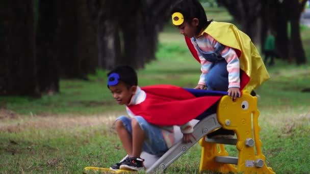 Två Små Asiatiska Barn Leker Lekplatsen Superhjältedräkter — Stockvideo