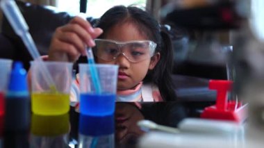 Asyalı küçük kız sıvı bilim laboratuarı deneyi yaparken eğleniyor.