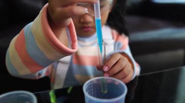 Asyalı küçük kız sıvı bilim laboratuarı deneyi yaparken eğleniyor.