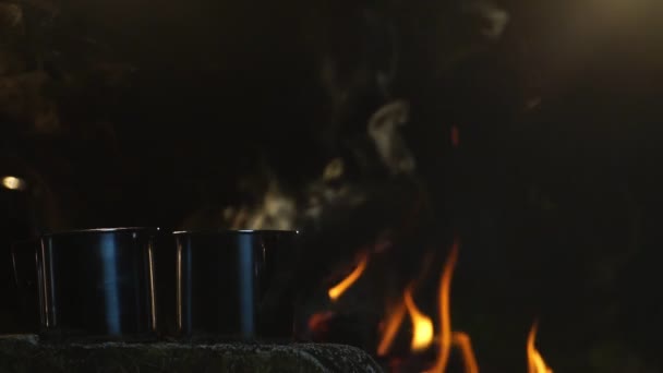 夜になるとキャンプファイア付近で熱い飲料を飲む金属カップ — ストック動画