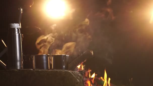 夜になるとキャンプファイア付近で熱い飲料を飲む金属カップ — ストック動画