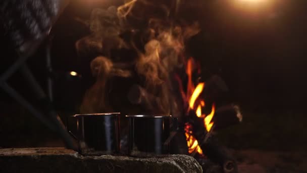 夜间在篝火边装有热饮的金属杯 — 图库视频影像