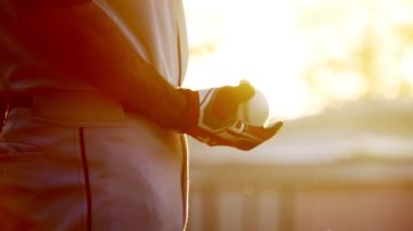 Gün batımında beyzbol eldiveni ve topla beyzbol oyuncusunun yavaş çekimleri, topu fırlatmaya gidiyor. 