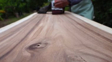 Male carpenter is using electric woodworking tool to work outdoors